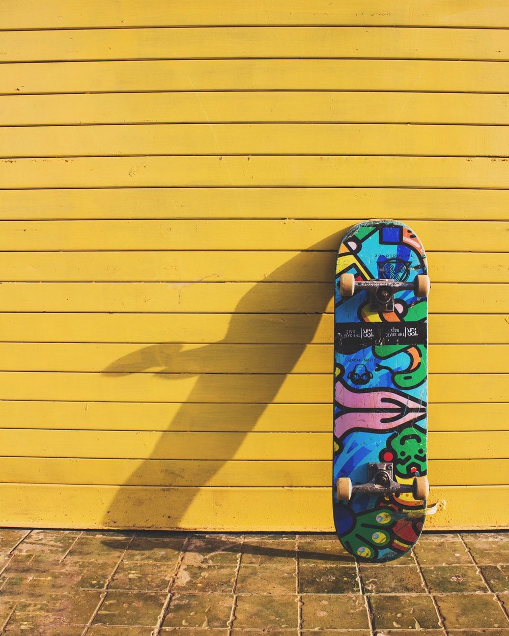 Skateboard colorato su parete gialla, 1000x1250 Verticale, iPhone Air